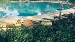 Un área de piscina con baldosas de piedra, sombrillas y sillas de descanso.