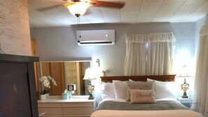 Un dormitorio con una cama de madera, un aparador, un espejo y un ventilador de techo.