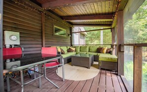 Un espace extérieur accueillant, aménagé avec une table et des chaises, un canapé confortable et offrant une vue sur la forêt environnante.