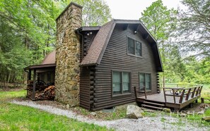 Une cabane en rondins avec une cheminée en pierre, une véranda et une terrasse.