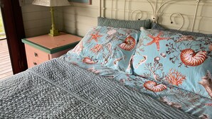 A bed with a blue and white patterned bedspread, a wooden headboard, and a nightstand with a lamp. - Private cottage in great location with a Path to Chocolate Hole Beach (St. John)