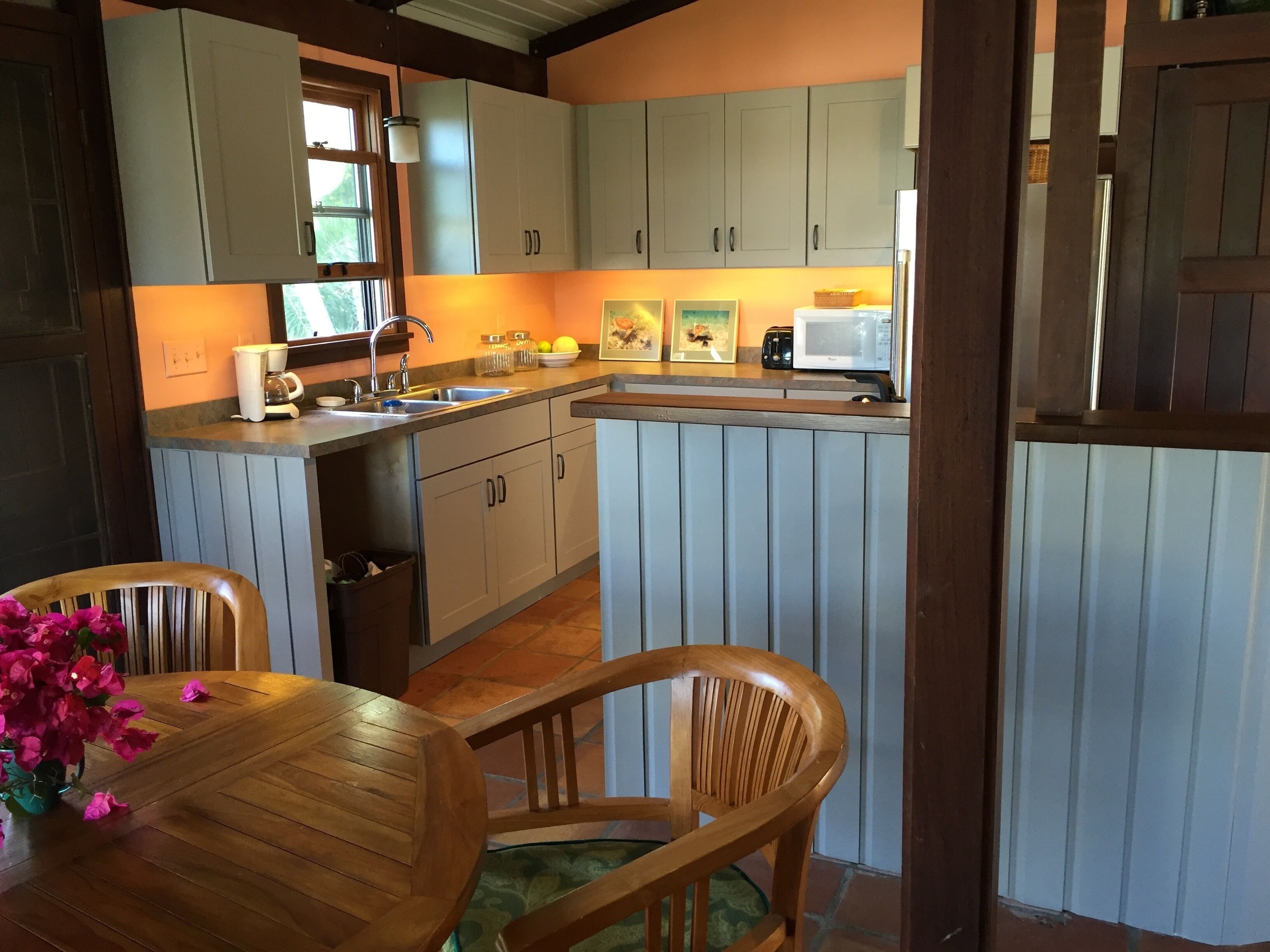 A kitchen with wooden cabinets, a sink, and a dining area with a table and chairs.