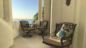 A balcony with a table and chairs, a view of the sea, and a palm tree. - Our gem on the beach. (San José del Cabo)