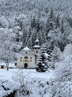 Eine schneebedeckte Kirche mit einem Glockenturm, umgeben von dichtem Wald.