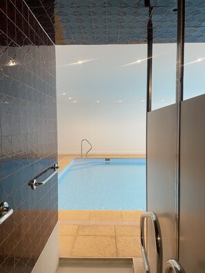 Ein Innenpool mit freier Sicht auf das Wasser, einer Metallhandstange und einer gefliesten Wand.