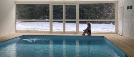 Una piscina con vistas a un paisaje nevado a través de amplios ventanales.