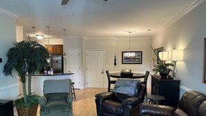 A living room with a sofa, armchair, and a coffee table. There is a dining table with chairs and a kitchen in the background. - 2 Bedrooms with king beds and private bathroom for both. (Charleston)