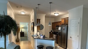 A modern kitchen with a central island, wooden cabinets, stainless steel appliances, and pendant lighting. - 2 Bedrooms with king beds and private bathroom for both. (Charleston)