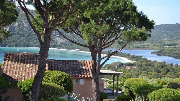 A coastal villa with a tiled roof, surrounded by lush greenery and overlooking a bay with a beach and mountains in the background. - SUPERB SEA VIEW over SANTA GIULIA bay in residence with private pool (Porto-Vecchio)