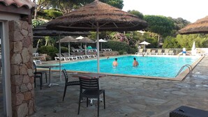 A swimming pool with lounge chairs and umbrellas, surrounded by stone walls and greenery. - SUPERB SEA VIEW over SANTA GIULIA bay in residence with private pool (Porto-Vecchio)