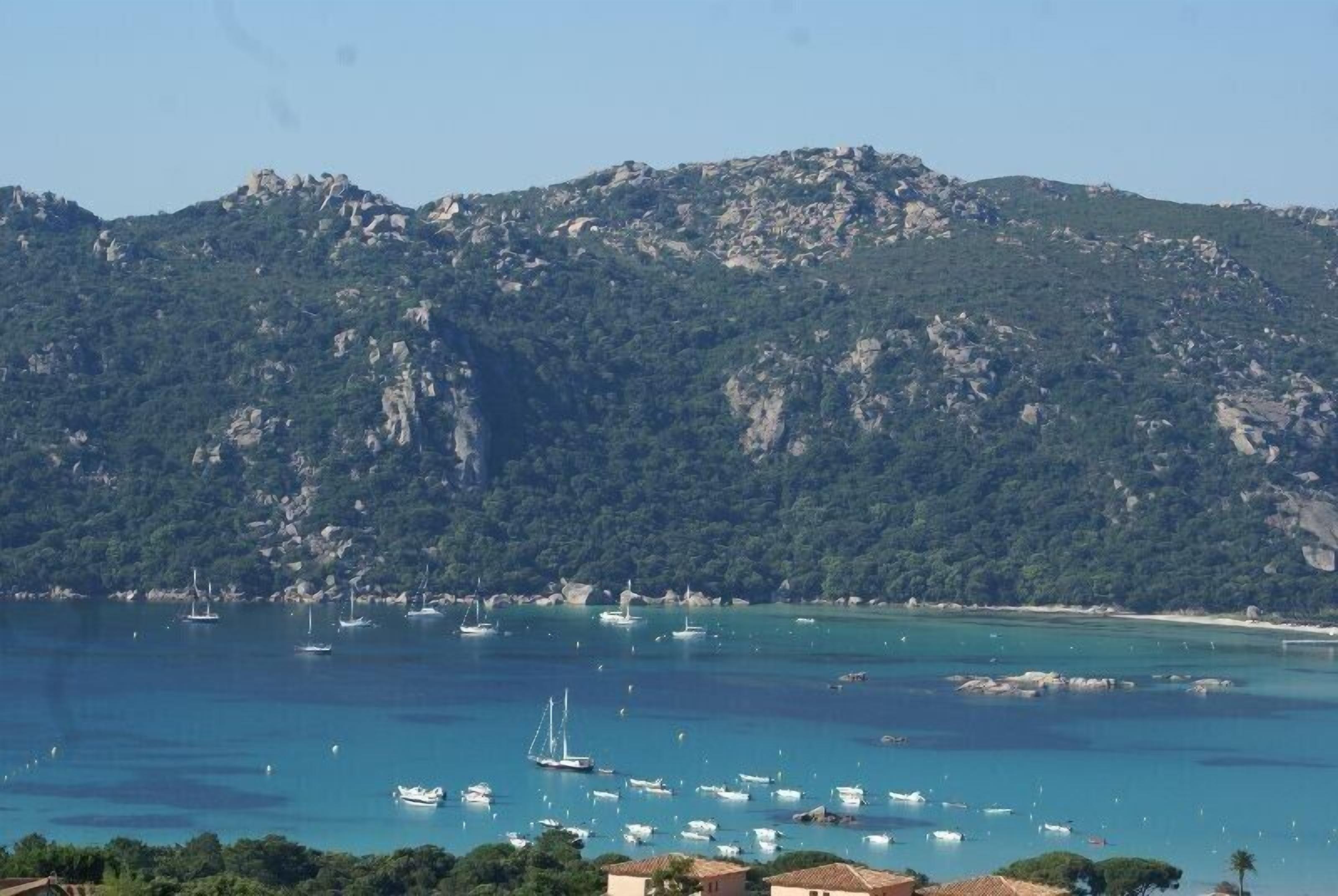 A coastal view with boats in the water and a mountainous backdrop.