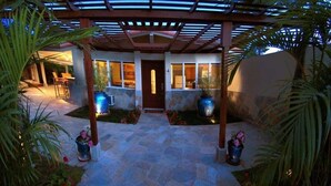 A covered patio area with stone flooring, potted plants, and a wooden pergola structure.