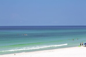 A beach with clear turquoise water, a sandy shore, and a few people in the water.
