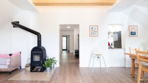 A modern interior with a wood-burning stove, a dining area, and a hallway leading to another room. - Alpine Escape Near Lake Bled – Breathtaking Views & Nature Trails (Žirovnica)
