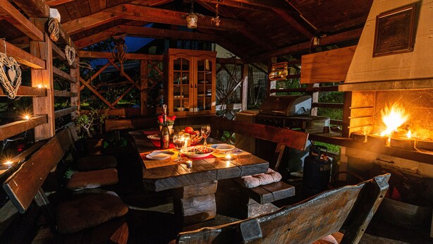 An outdoor dining area with wooden furniture, a fire feature, and a view of the surrounding landscape. - Alpine Escape Near Lake Bled – Breathtaking Views & Nature Trails (Žirovnica)