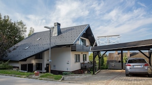 A modern two-story house with a sloped roof, a covered driveway, and a parked car. - Alpine Escape Near Lake Bled – Breathtaking Views & Nature Trails (Žirovnica)