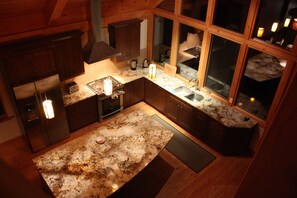 A modern kitchen with wooden cabinets, granite countertops, and a large island. - Kicking Horse ski Chalet Great views,2 wood fires, hot tub, sauna, heated floor (Golden)