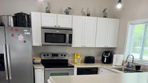 A modern kitchen with white cabinets, stainless steel appliances, a central island, and pendant lighting. - waterfront beach retreat with boat dock (Ocean Pines)