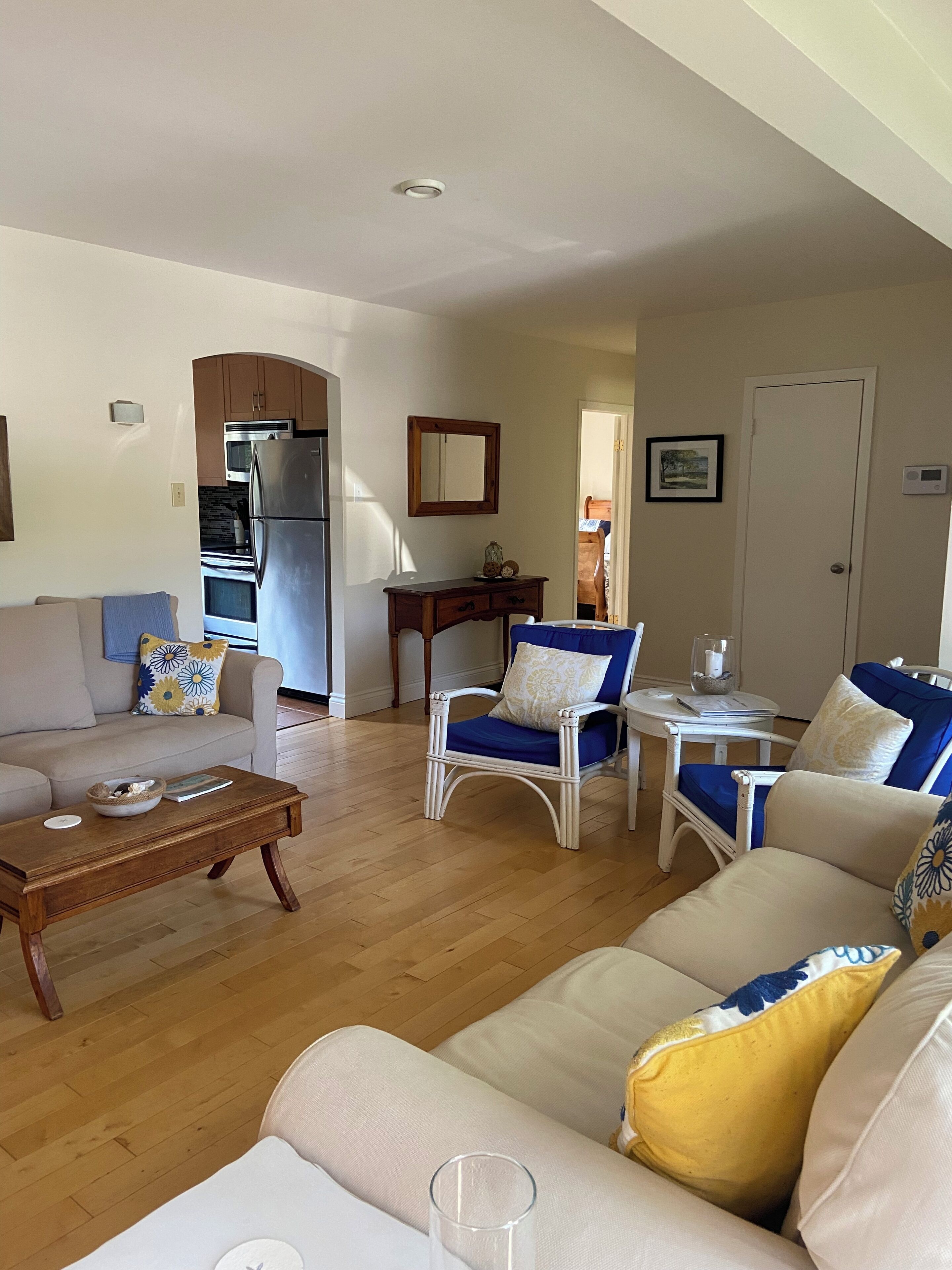 Een woonkamer met een bank, fauteuils, een salontafel en een eethoek met een tafel en stoelen.