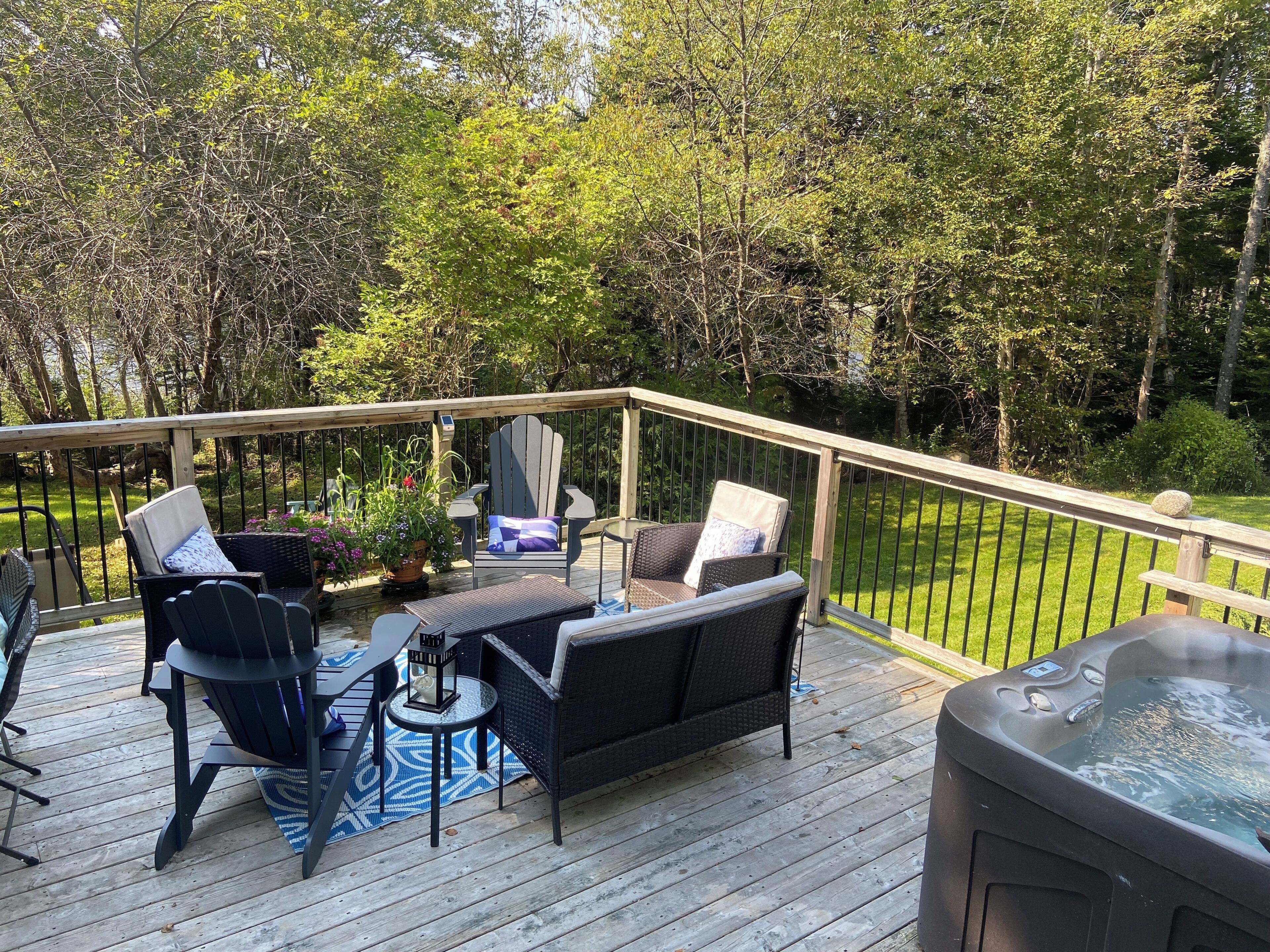 Une terrasse en bois, agrémentée de mobilier d’extérieur, notamment des chaises et une table, et entourée d’une rambarde en métal.