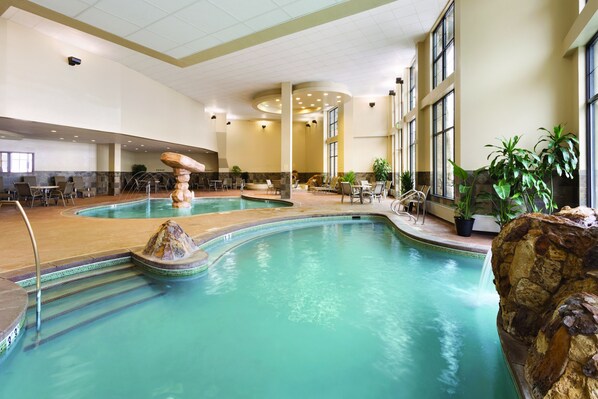 An indoor swimming pool with multiple lanes, seating areas, and a central rock feature. - New Year's Breckenridge Ski In Ski Out -Luxury Condo. Sleeps 12 Dec 27 -Jan 3rd (Breckenridge)