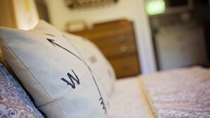 Primer plano de un almohadón con diseño textil y una cama con colcha estampada.