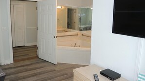 A bathroom with a bathtub, a mirror, and a TV mounted on the wall. - 503l Studio Bedroom Villa by RedAwning (Calabash)