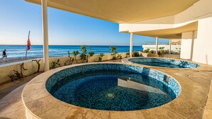 Área da piscina com vista para o mar, um espaço de estar coberto e uma bandeira.