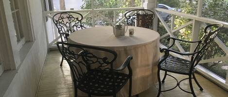 A round table with a beige tablecloth surrounded by four black metal chairs.