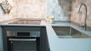 Una cocina con horno empotrado, un lavamanos y un grifo moderno.