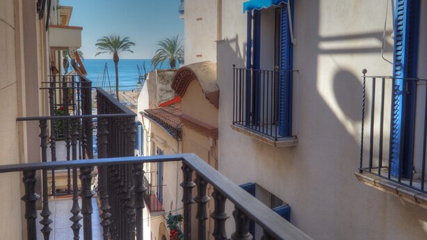A narrow street with balconies overlooking a beach. - Balcony View Apartment by Hello Homes Sitges (Sitges)