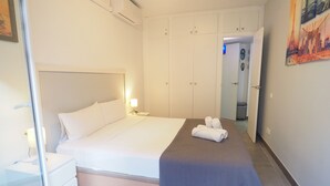 Una habitación de hotel con una cama, mesitas de noche, un armario y un cuadro en la pared.