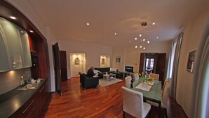Un grand espace de vie comprenant un coin repas avec une table et des chaises, un canapé et un coin cuisine équipé d’un réfrigérateur et d’un four.