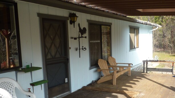 A wooden porch with two Adirondack chairs, a small table, and a covered area. - End of the road .... (Mariposa)