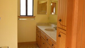 A bathroom with wooden cabinets, a sink, a mirror, and a window. - End of the road .... (Mariposa)