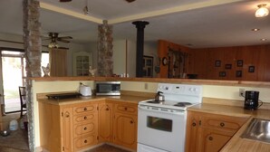 A kitchen with wooden cabinets, a white stove, a microwave, and a coffee maker. - End of the road .... (Mariposa)