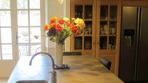 A kitchen with a large island, wooden cabinets, a stainless steel sink, and a vase with flowers. - Gordes/Goult - Stunning Mas Provençal On A Hill In Luderon (Goult)