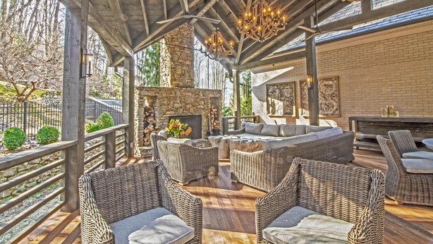 Eine Terrasse im Freien mit Korbmöbeln, Steinpfeilern und einem Kamin.