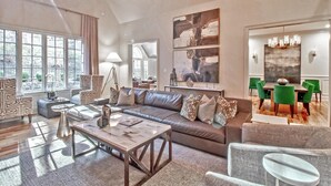 Ein geräumiges Wohnzimmer mit einem großen Ecksofa, einem Couchtisch und einem Essbereich mit Tisch und Stühlen.