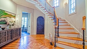 Eine imposante Treppe mit Holzboden und schwarzen Spindeln, die zu einer oberen Etage führt.