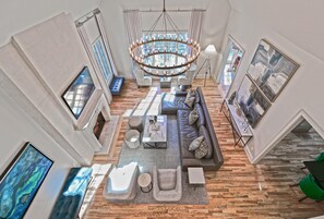 Relax in a spacious living area with a high ceiling, featuring a comfortable seating area and large windows.