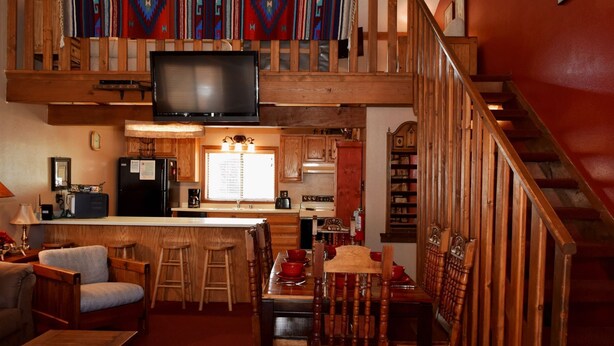 Un espace de vie chaleureux de style loft, comprenant une cuisine, un coin repas et un escalier.