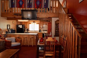 A cozy loft-style living space with a kitchen, dining area, and a staircase.