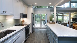 A modern kitchen with white cabinetry, stainless steel appliances, and a large island. - SeaPines, Stunning, Pet friendly, Golf view, Walk to SeaPines Beach Club (Hilton Head Island)