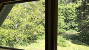Janela com vista para uma área arborizada e um corpo d'água.
