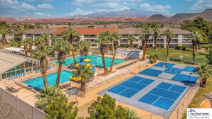 A resort with a swimming pool, basketball courts, and palm trees.