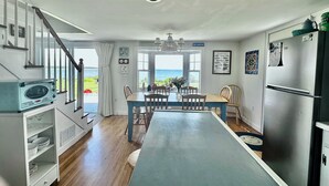 A kitchen with a dining area, a view of the sea, and a staircase leading to another level.