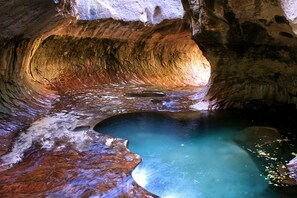 Una cueva con una poza natural y un interior rocoso.