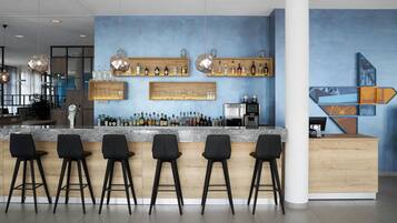 A modern bar area with a marble countertop, black bar stools, and shelves with bottles and glasses.