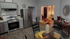 A modern kitchen with stainless steel appliances, a dining area with a glass table and chairs, and a ceiling light fixture. - Adorable Intown Duplex Close to Downtown Atlanta; 5 minute walk to Beltline (Atlanta)